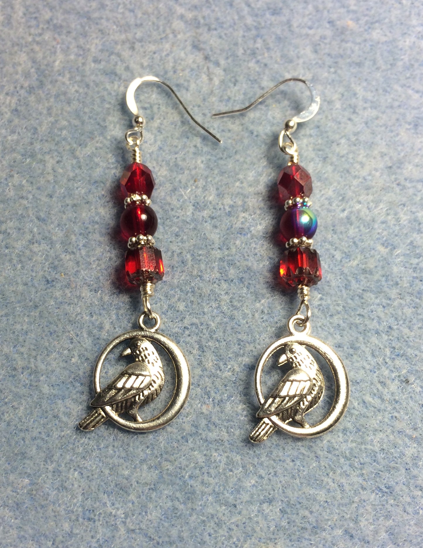 Silver raven charm earrings adorned with red Czech glass lentil beads.