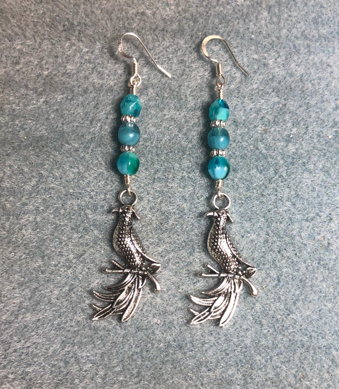 Long silver phoenix charm earrings adorned with milky turquoise Czech glass beads