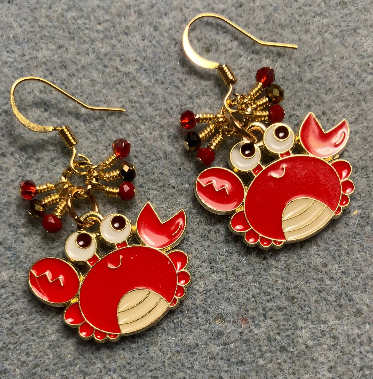 Large red, black, and white enamel crab charm earrings adorned with tiny dangling red and gold Chinese crystal beads.