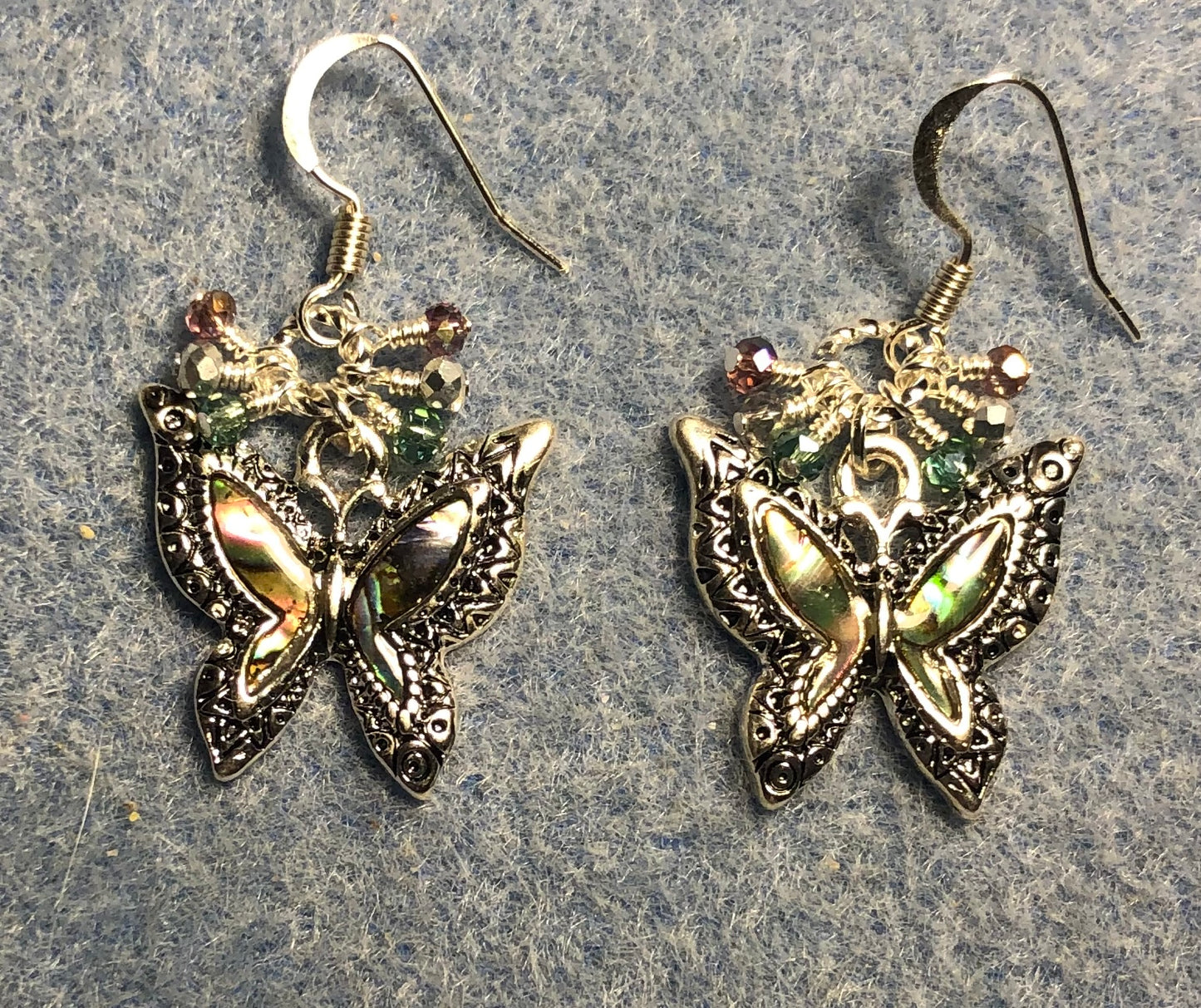 Silver and abalone butterfly charm earrings adorned with tiny dangling green, silver, and violet Chinese crystal beads.