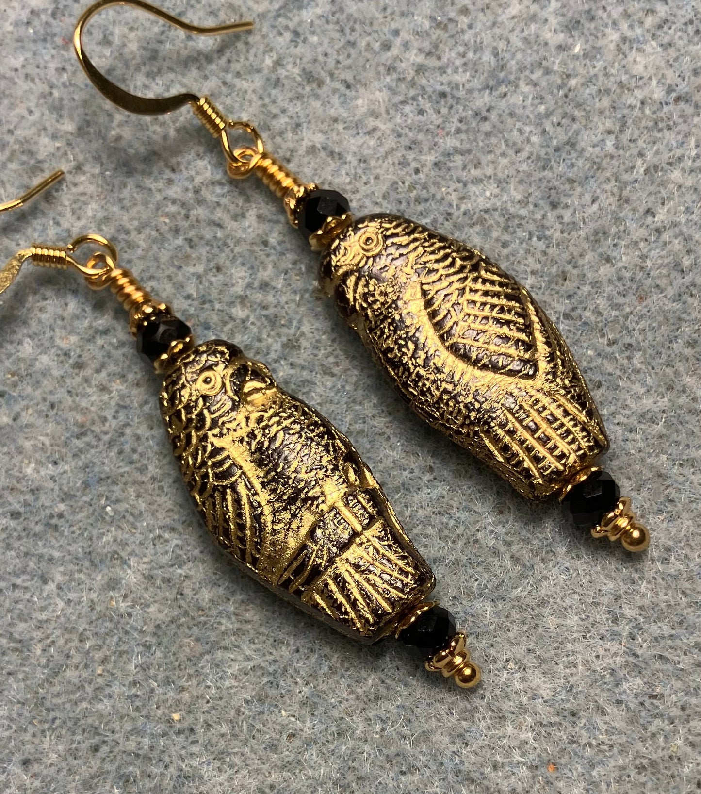 Large black (with gold wash) Czech glass parrot bead earrings adorned with black Chinese crystal beads.