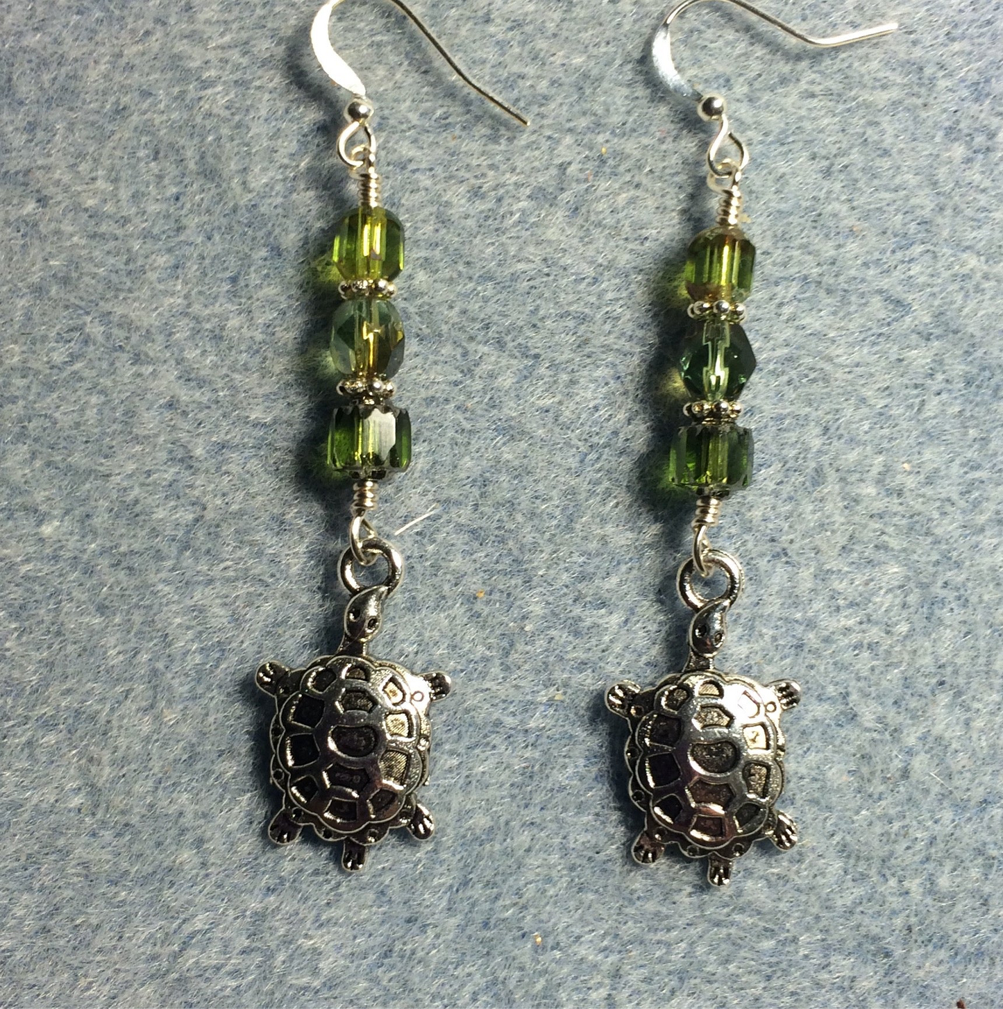 Silver turtle charm earrings adorned with olive green Czech glass beads