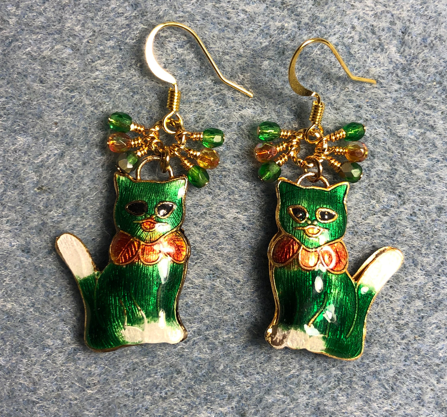 Dark green, orange, and white cloisonné cat charm earrings adorned with small dangling dark green and orange Czech glass beads.