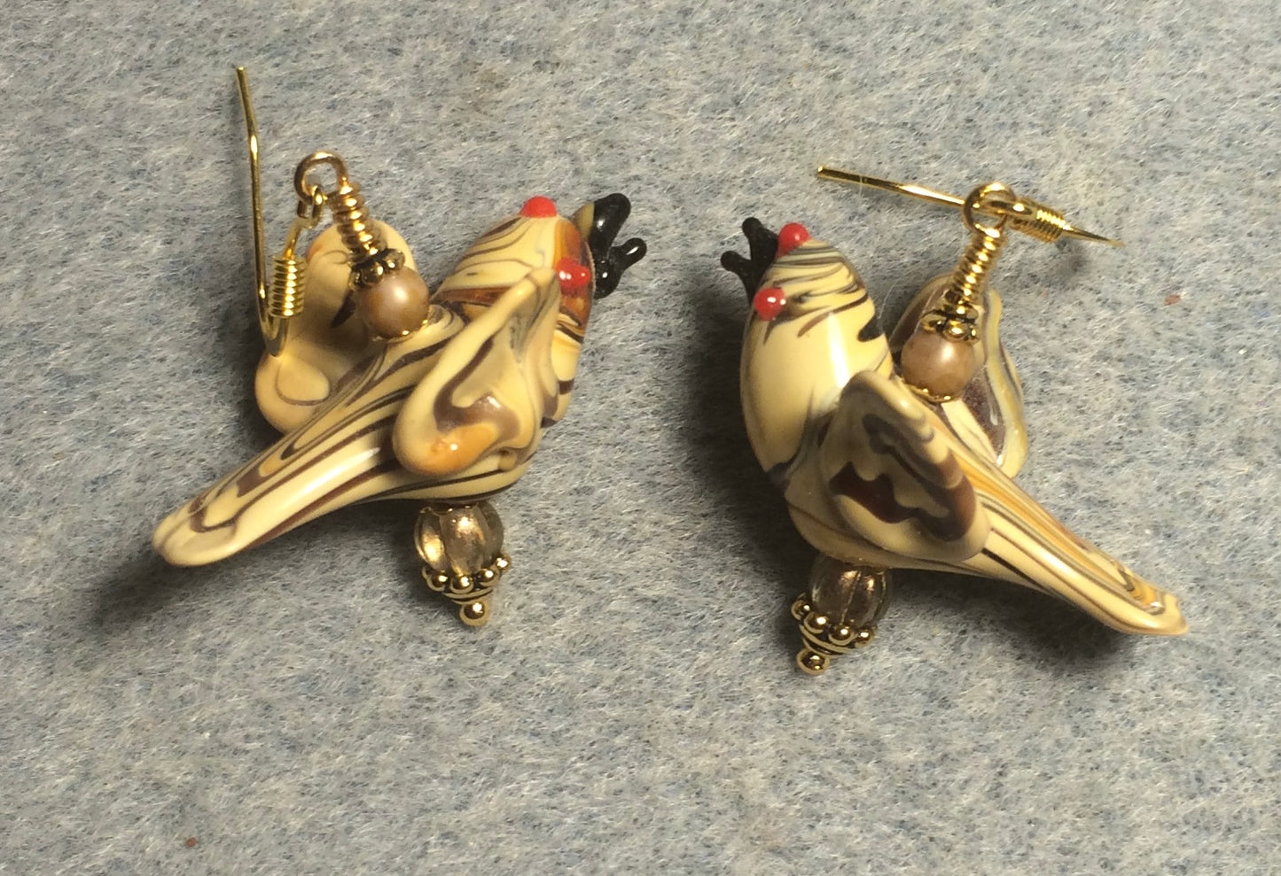 Tan lamp work striped flying bird bead earrings adorned with tan Czech glass beads.
