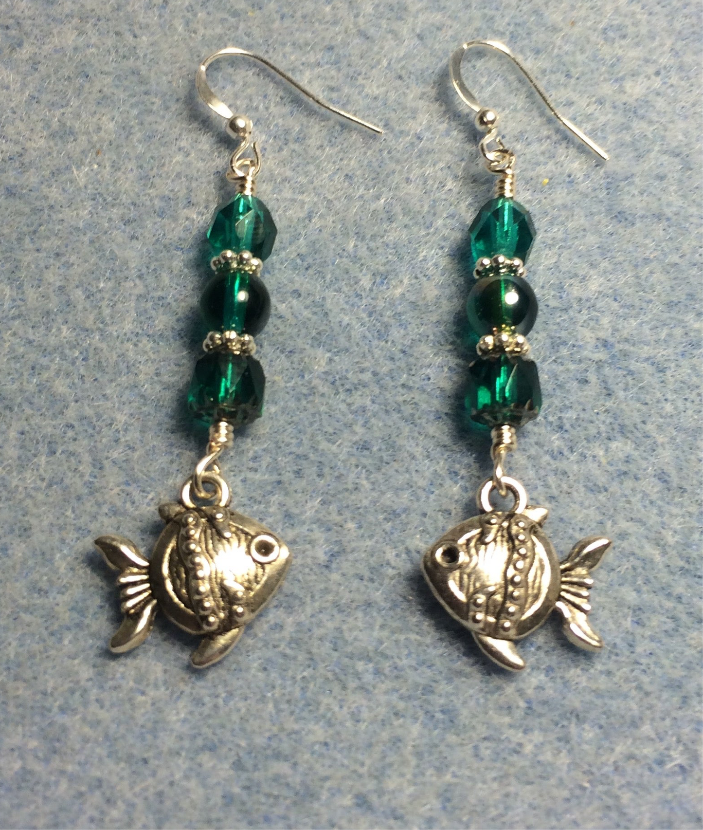 Silver angelfish charm earrings adorned with teal Czech glass beads.