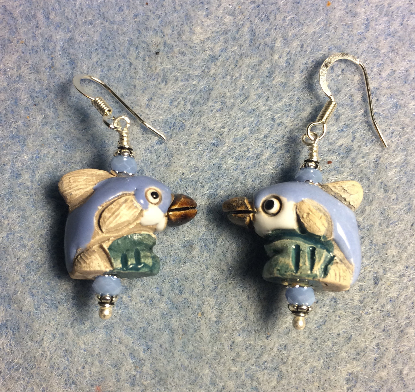Small light blue, tan, and green ceramic dolphin bead earrings adorned with light blue Chinese crystal beads.