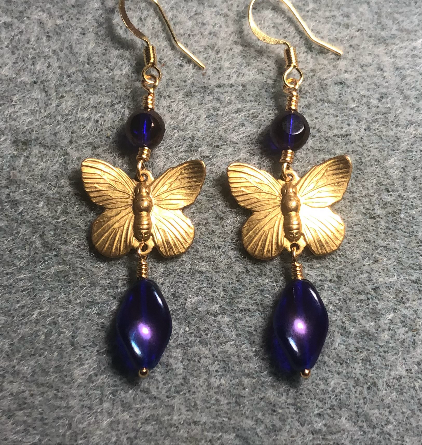 Gold butterfly charm connector earrings adorned with metallic blue Czech glass twist beads and blue gold Czech glass beads.