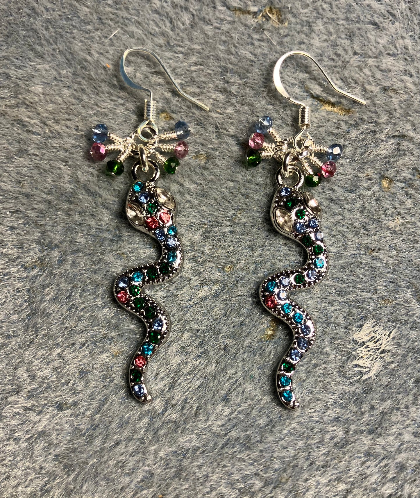 Silver and colored rhinestone coiled snake charm earrings adorned with tiny dangling pink, blue, and green Chinese crystal beads.