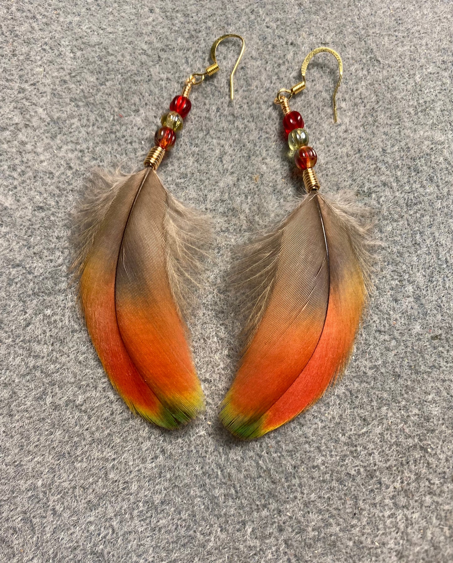 Small bright red scarlet macaw feather earrings adorned with small red and green Czech glass beads.