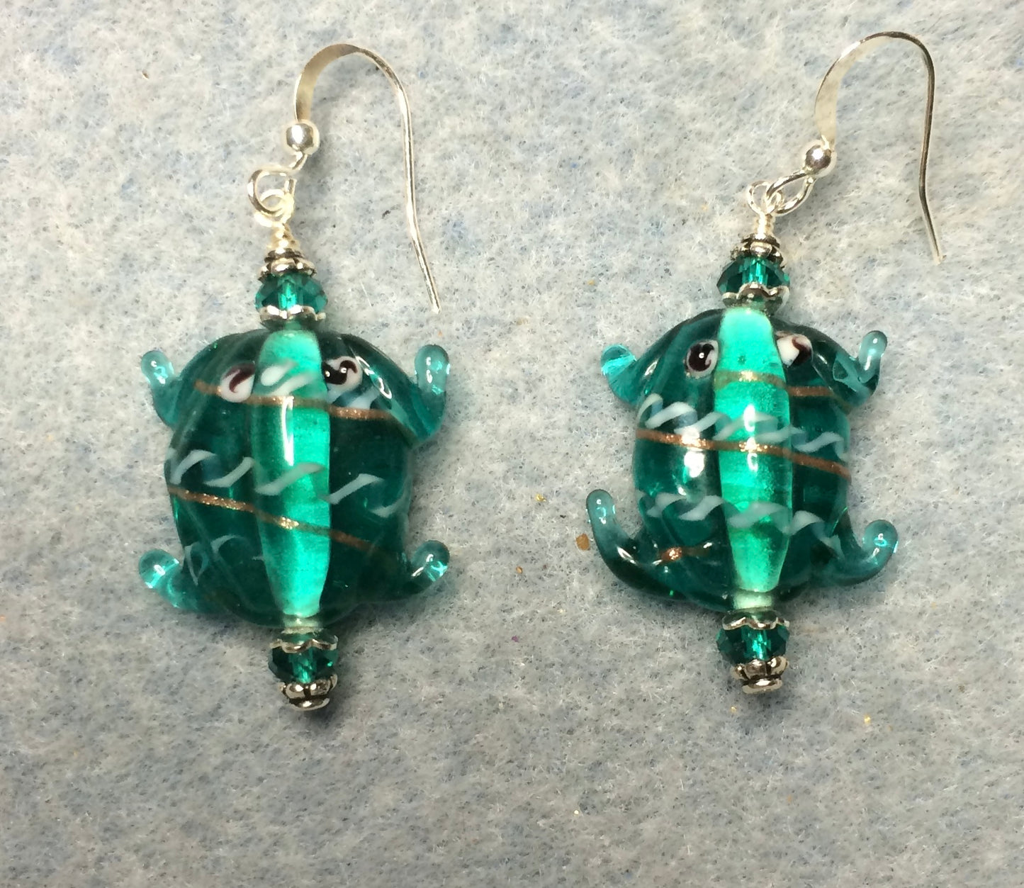 Teal lamp work frog bead earrings adorned with teal Chinese crystal beads.