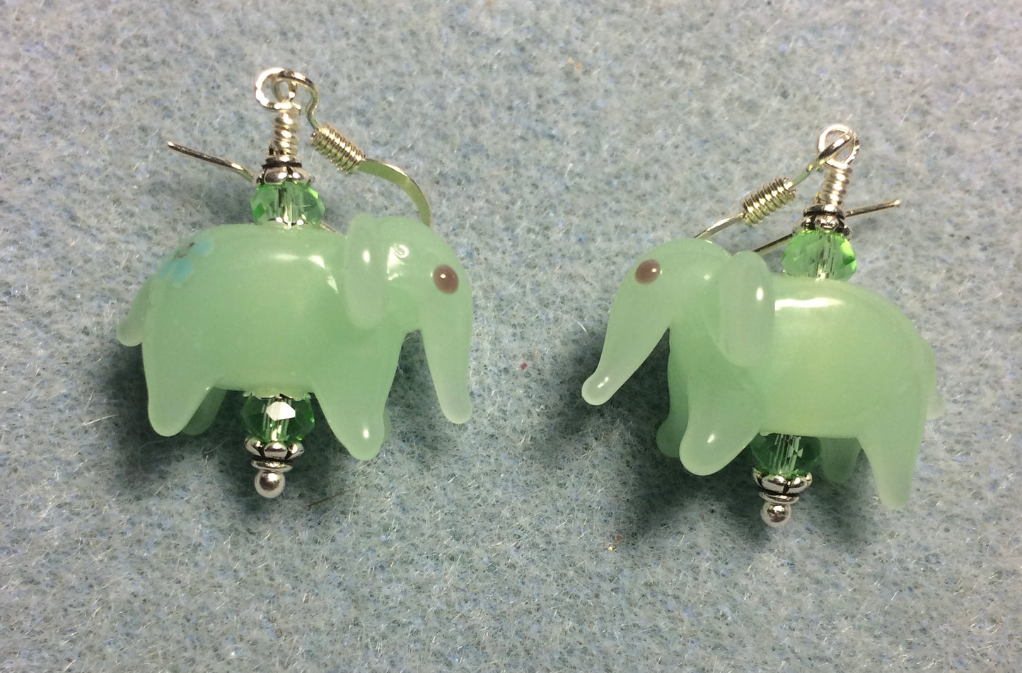 Opaque light green lamp work elephant bead earrings adorned with light green Chinese crystal beads.