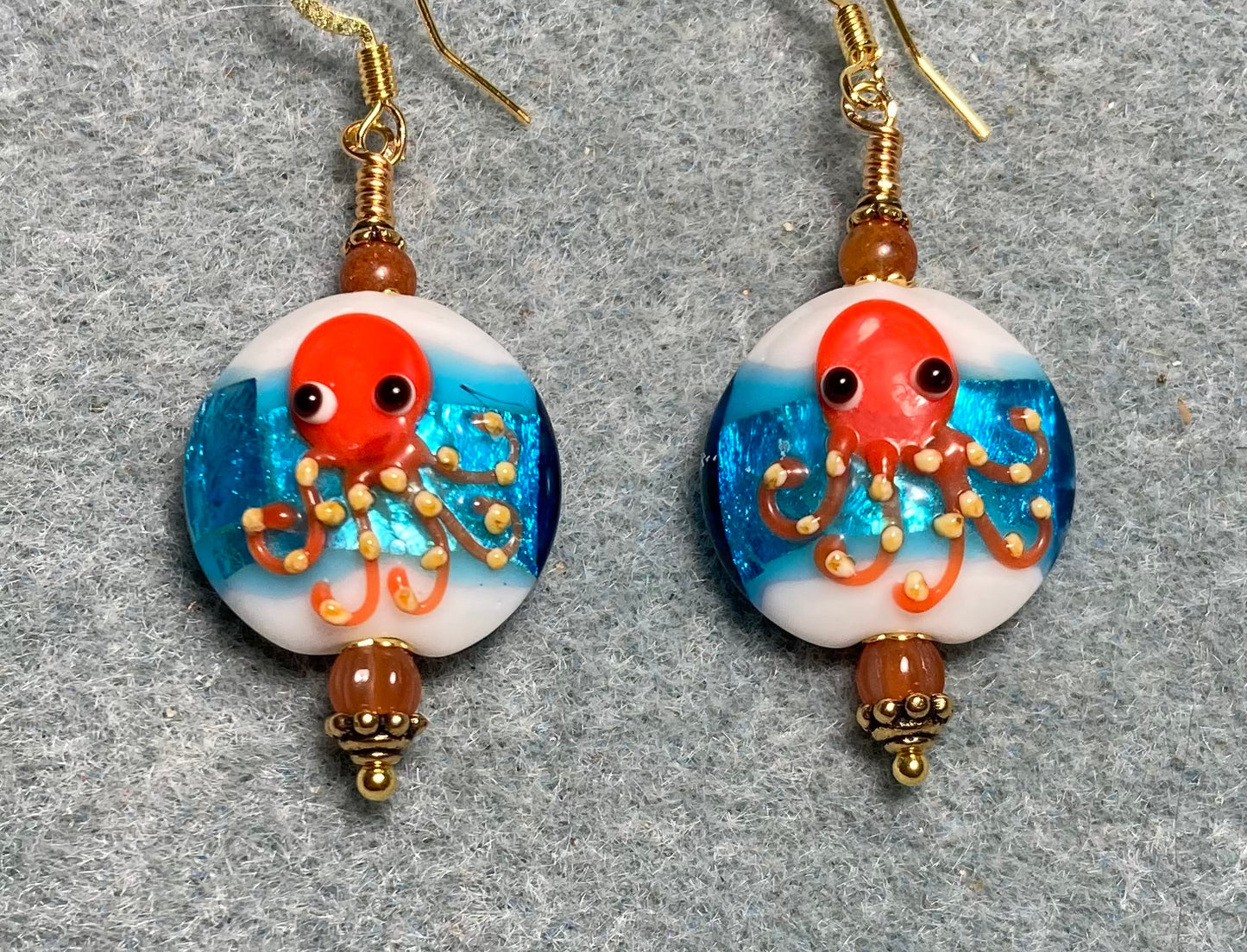 Turquoise, white, and orange lamp work octopus bead earrings adorned with orange Czech glass beads.