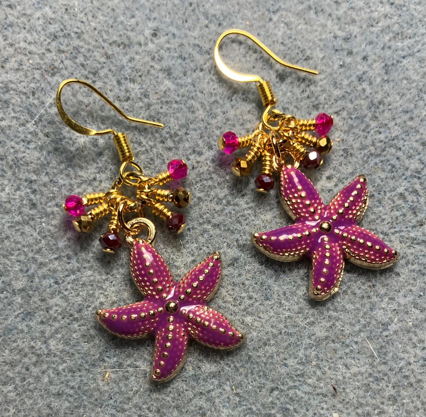 Dark pink and gold enamel starfish charm earrings adorned with tiny dangling dark pink and gold Chinese crystal beads.