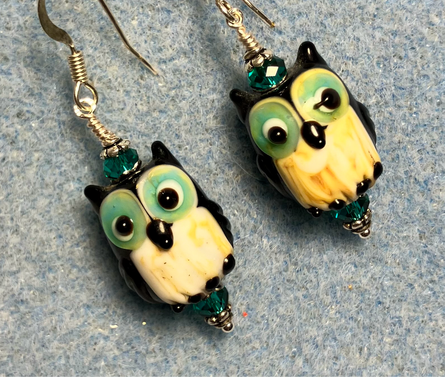 Teal, white, and black lamp work owl bead earrings adorned with teal Chinese crystal beads.