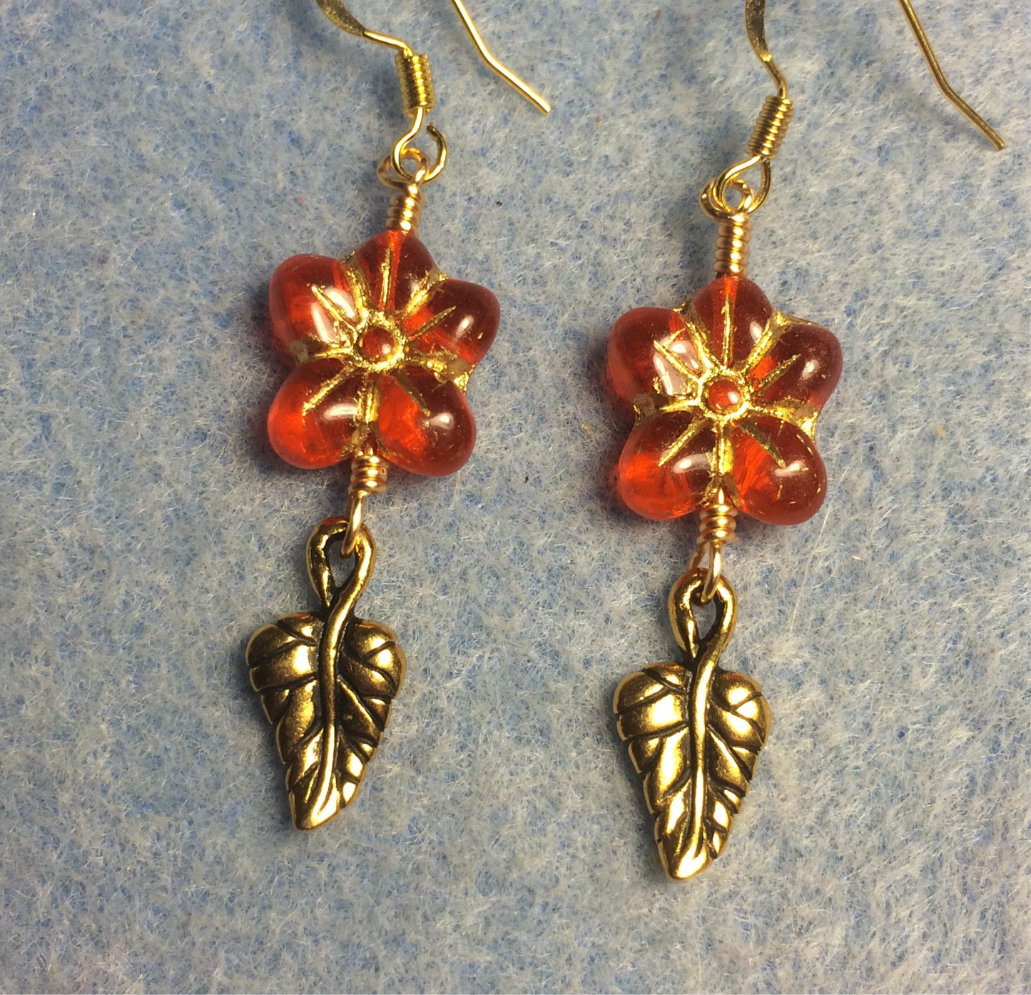Orange red (with gold inlay) Czech glass puffy flower bead earrings adorned with gold Tierracast leaf charms.