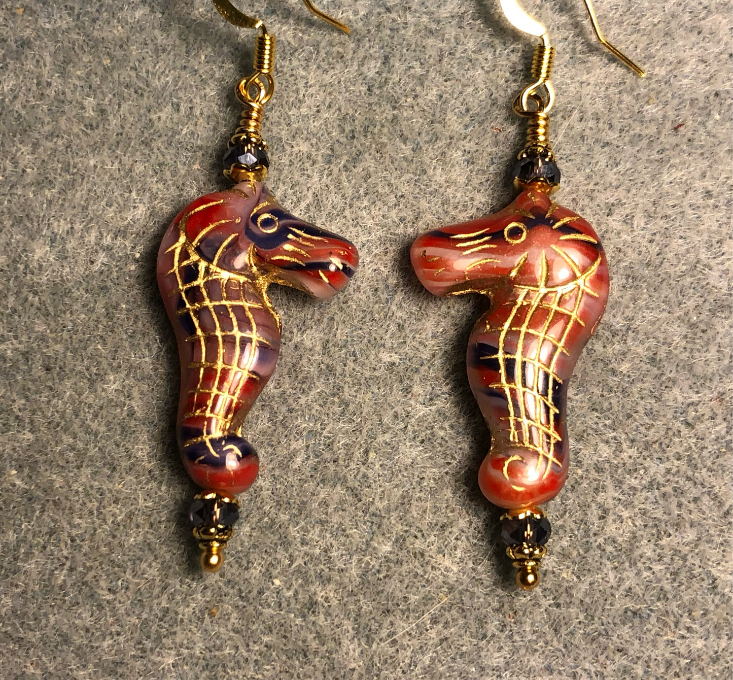 Reddish orange and purple (with gold inlay) Czech glass seahorse bead earrings adorned with purple Chinese crystal beads.