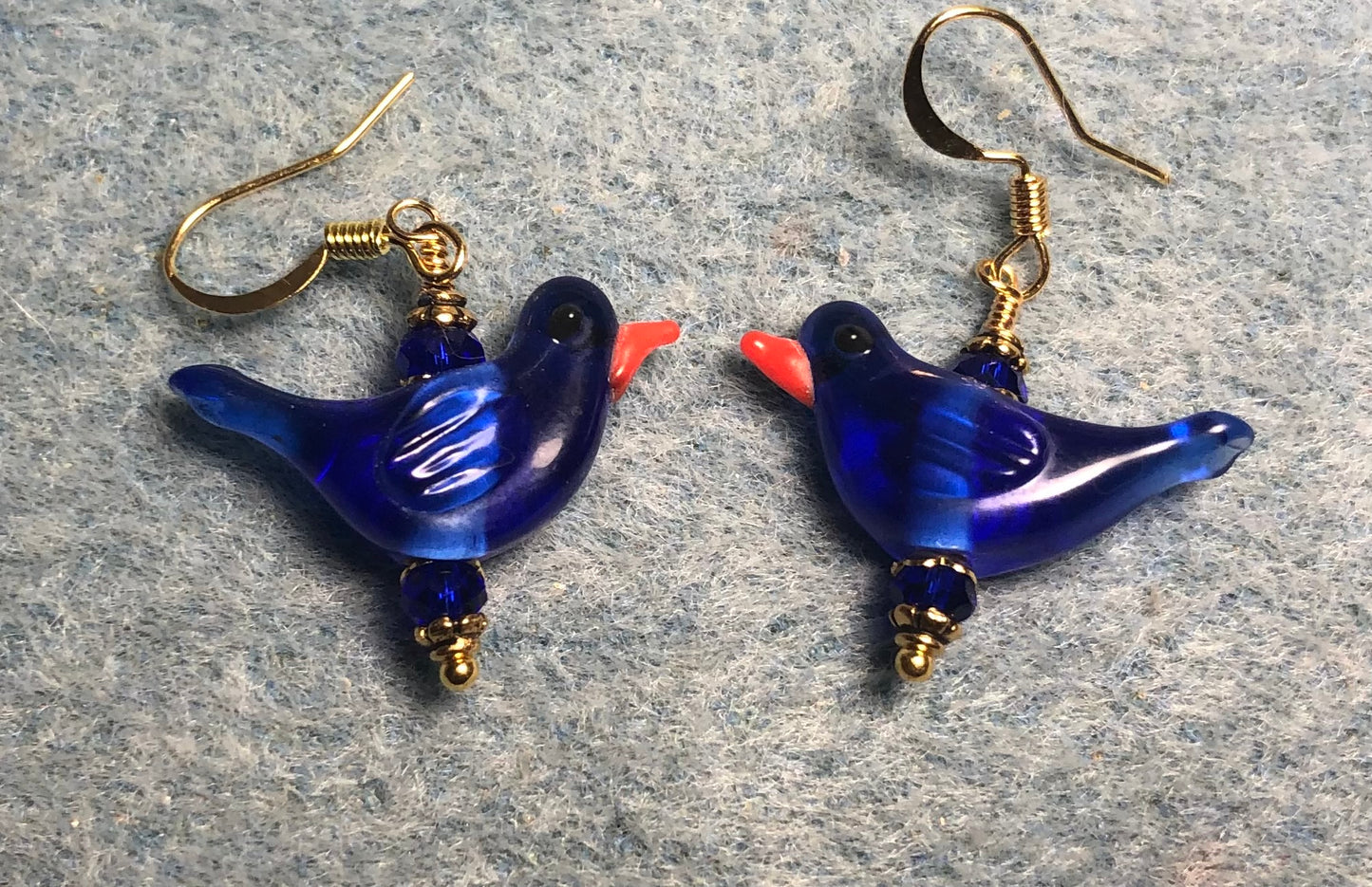 Translucent dark blue lamp work songbird bead earrings adorned with dark blue Chinese crystal beads.