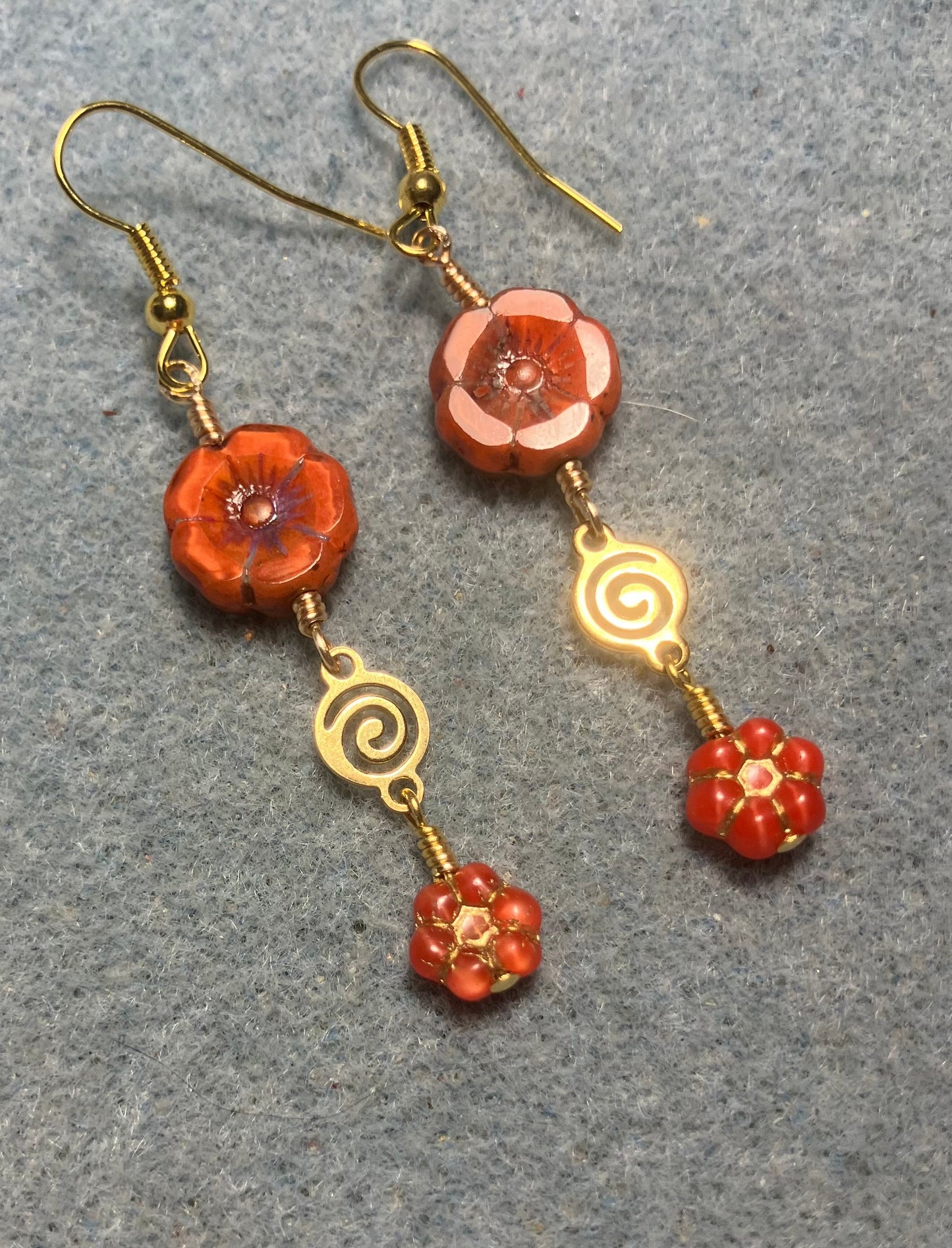 Orange Czech glass pansy bead earrings adorned with gold swirly connectors and tiny orange Czech glass daisy beads.