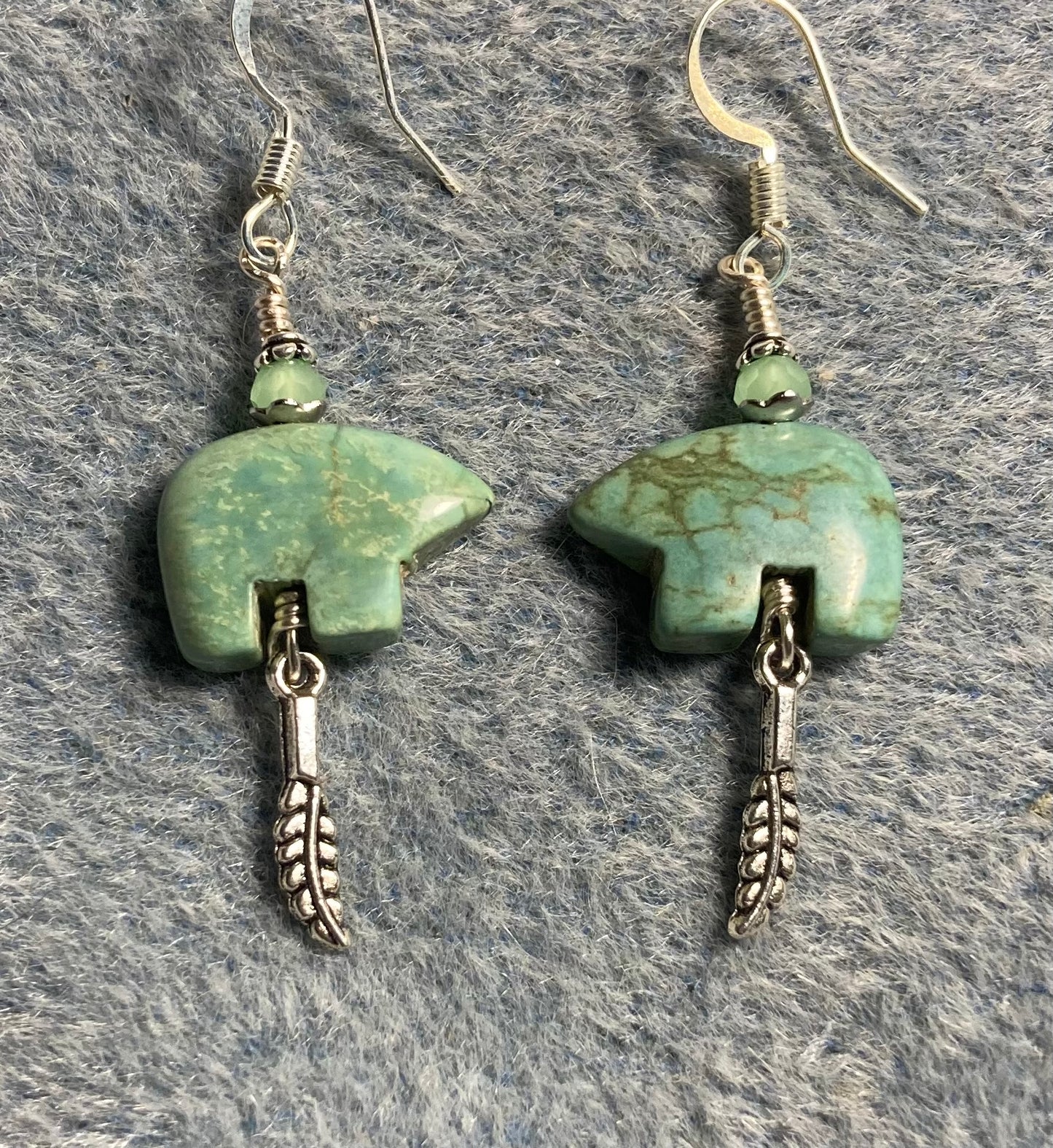 Green turquoise gemstone Zuni bear fetish bear earrings adorned with light green crystal beads and tiny silver feather charms.