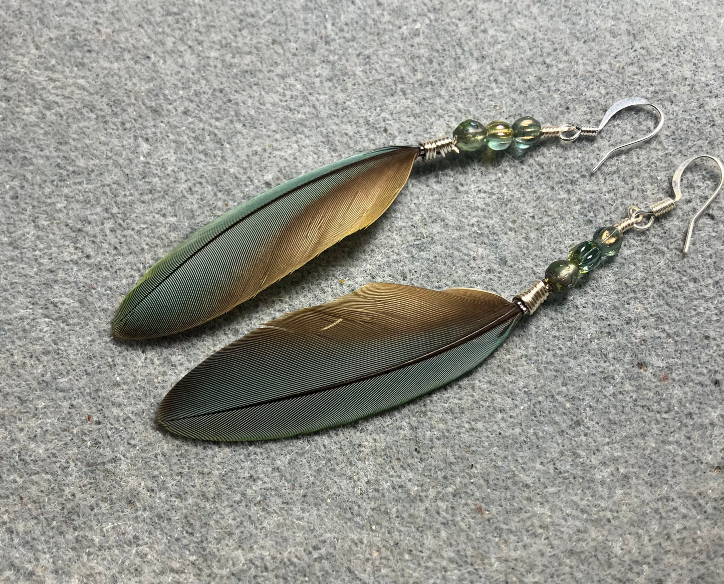 Small pointed green gray red-fronted macaw feather earrings adorned with small green gray Czech glass beads.