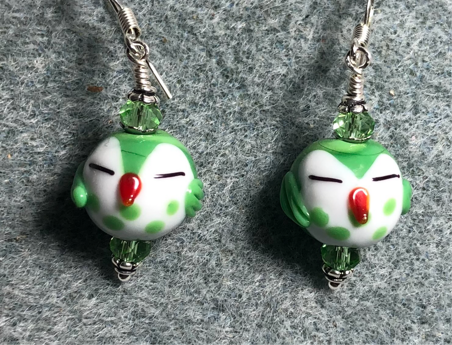 Small green and white lamp work sleepy owl bead earrings adorned with green Chinese crystal beads.