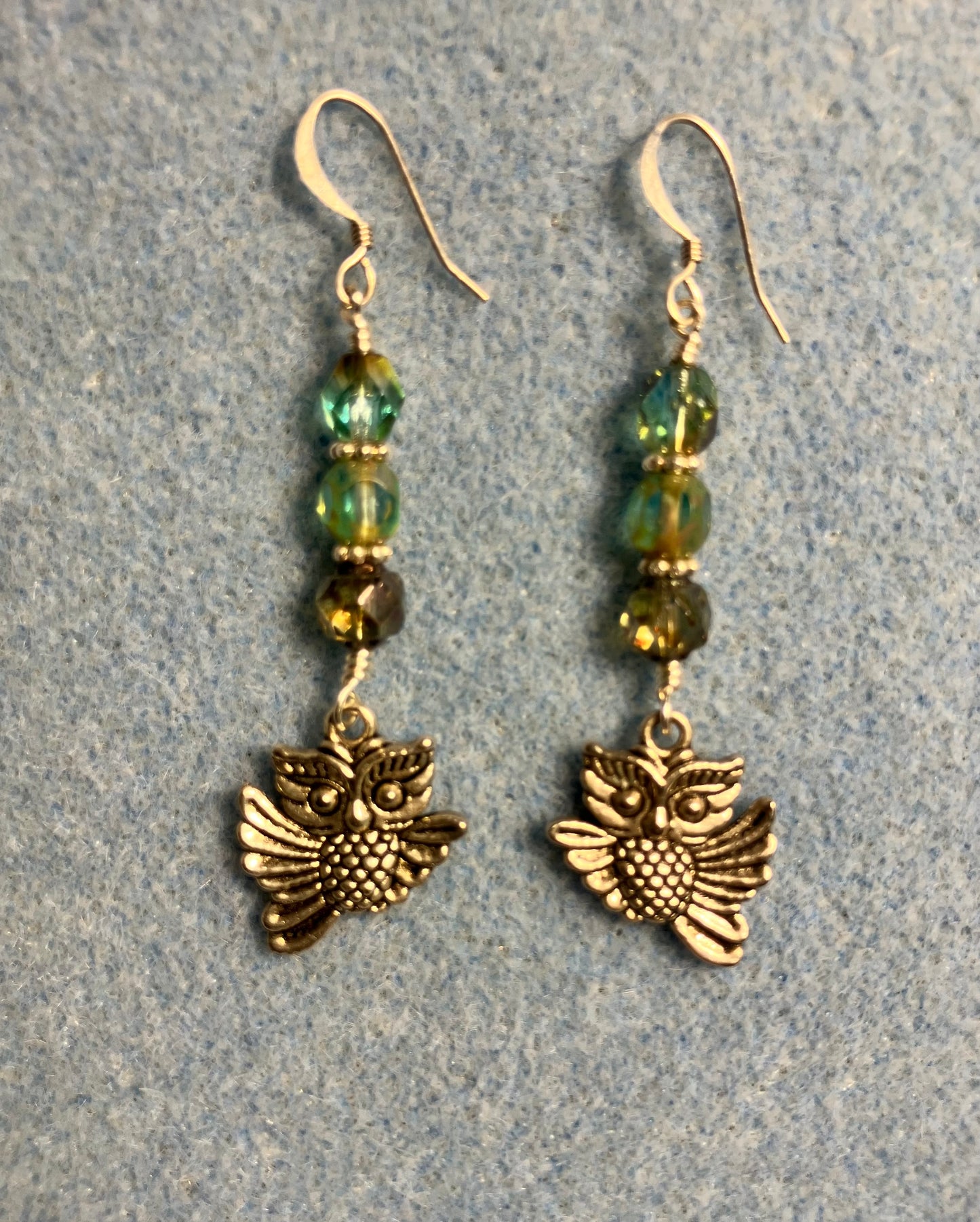 Silver owl charm earrings adorned with blue green Czech glass melon beads.