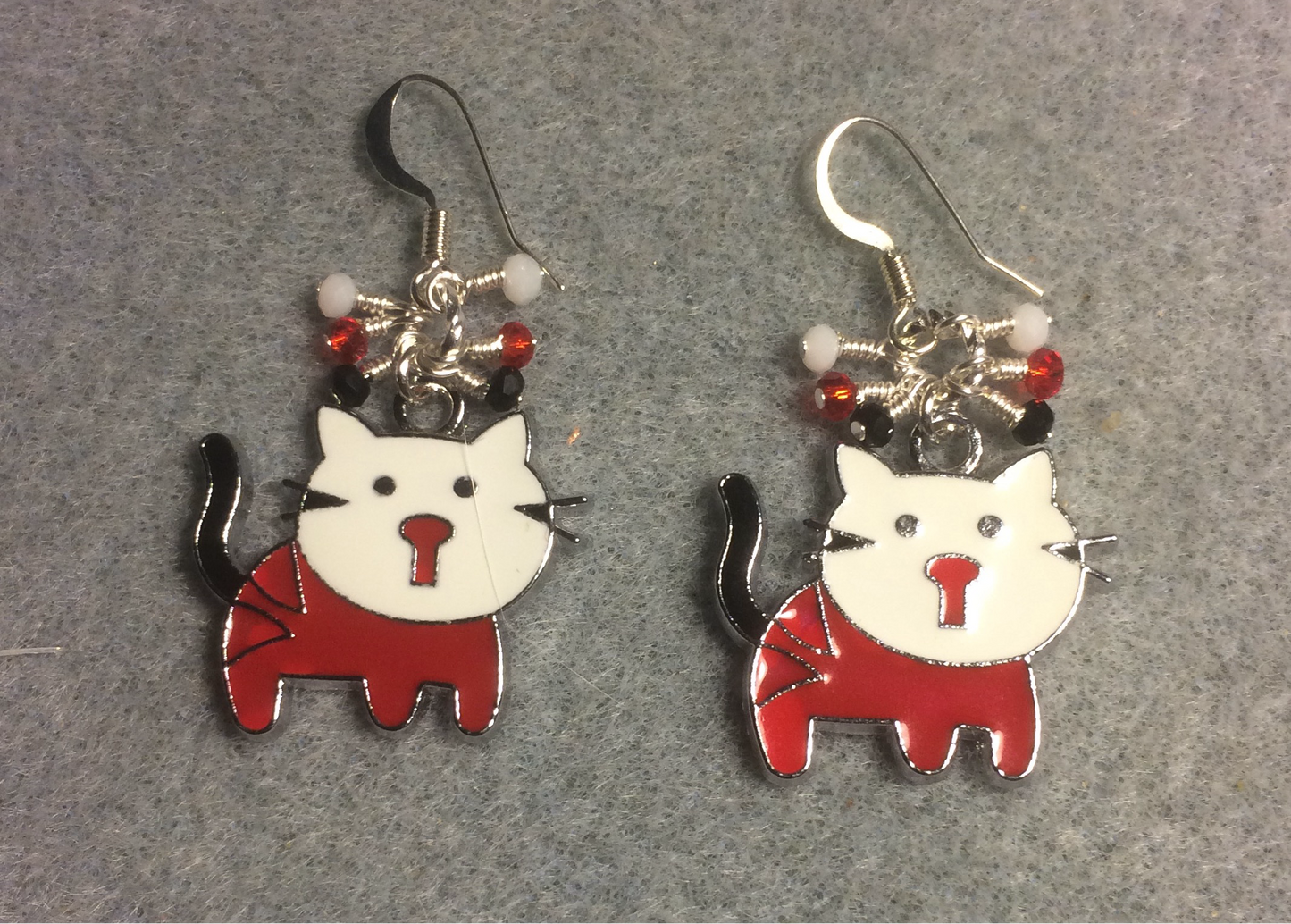 Red, white, and black enamel cat charm earrings adorned with tiny dangling red, white, and black Chinese crystal beads.