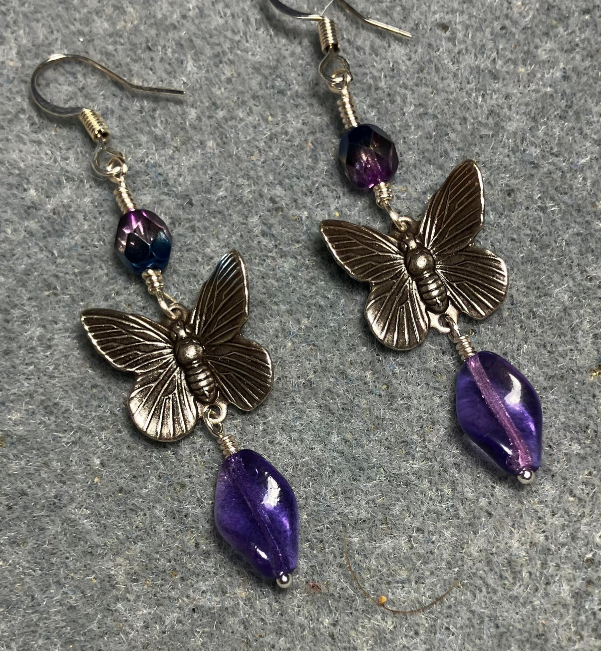 Silver butterfly charm connector earrings adorned with purple Czech glass twist beads and purple Czech glass beads.