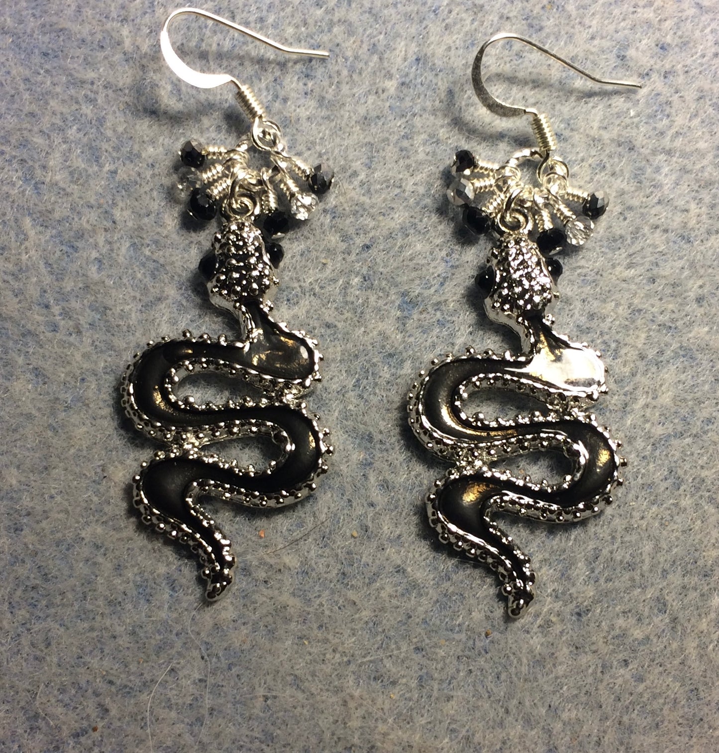 Black enamel coiled snake charm earrings adorned with tiny dangling black and silver Chinese crystal beads.