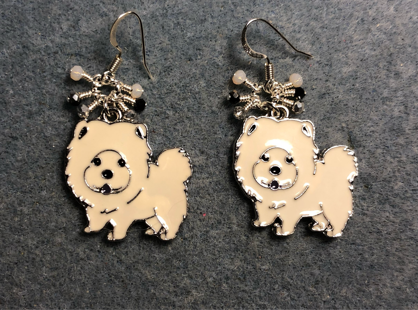 White enamel Chow dog charm earrings adorned with tiny dangling white, black, and silver Chinese crystal beads.