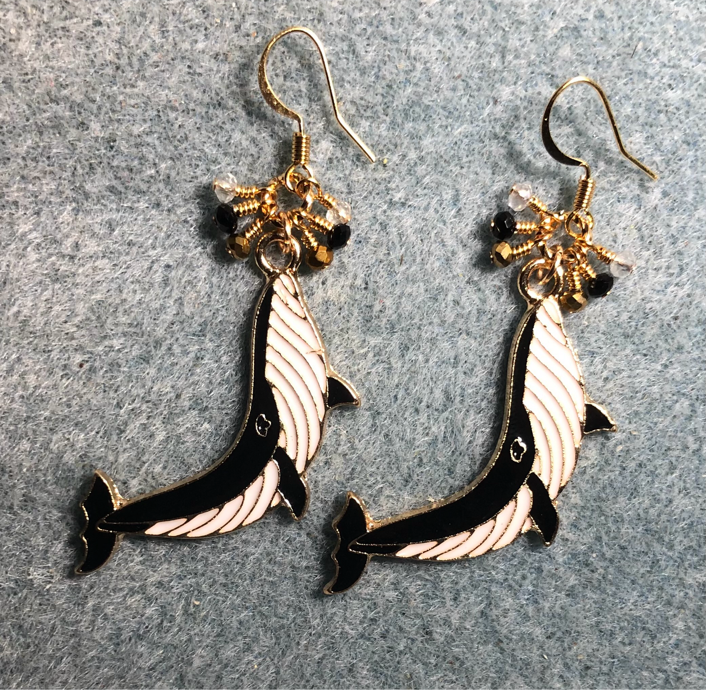 Long black and white enamel whale charm earrings adorned with tiny dangling black, white, and gold Chinese crystal beads.