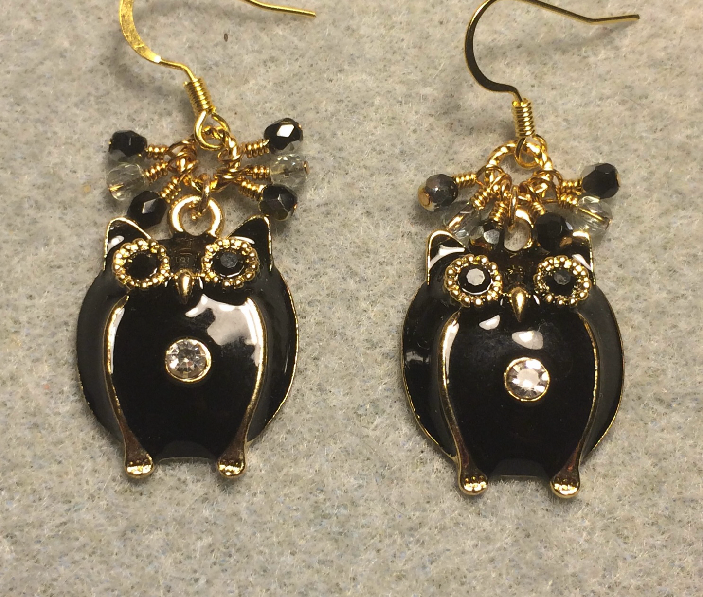 Large gold and black enamel and rhinestone owl charm earrings adorned with small dangling black and clear Czech glass beads.