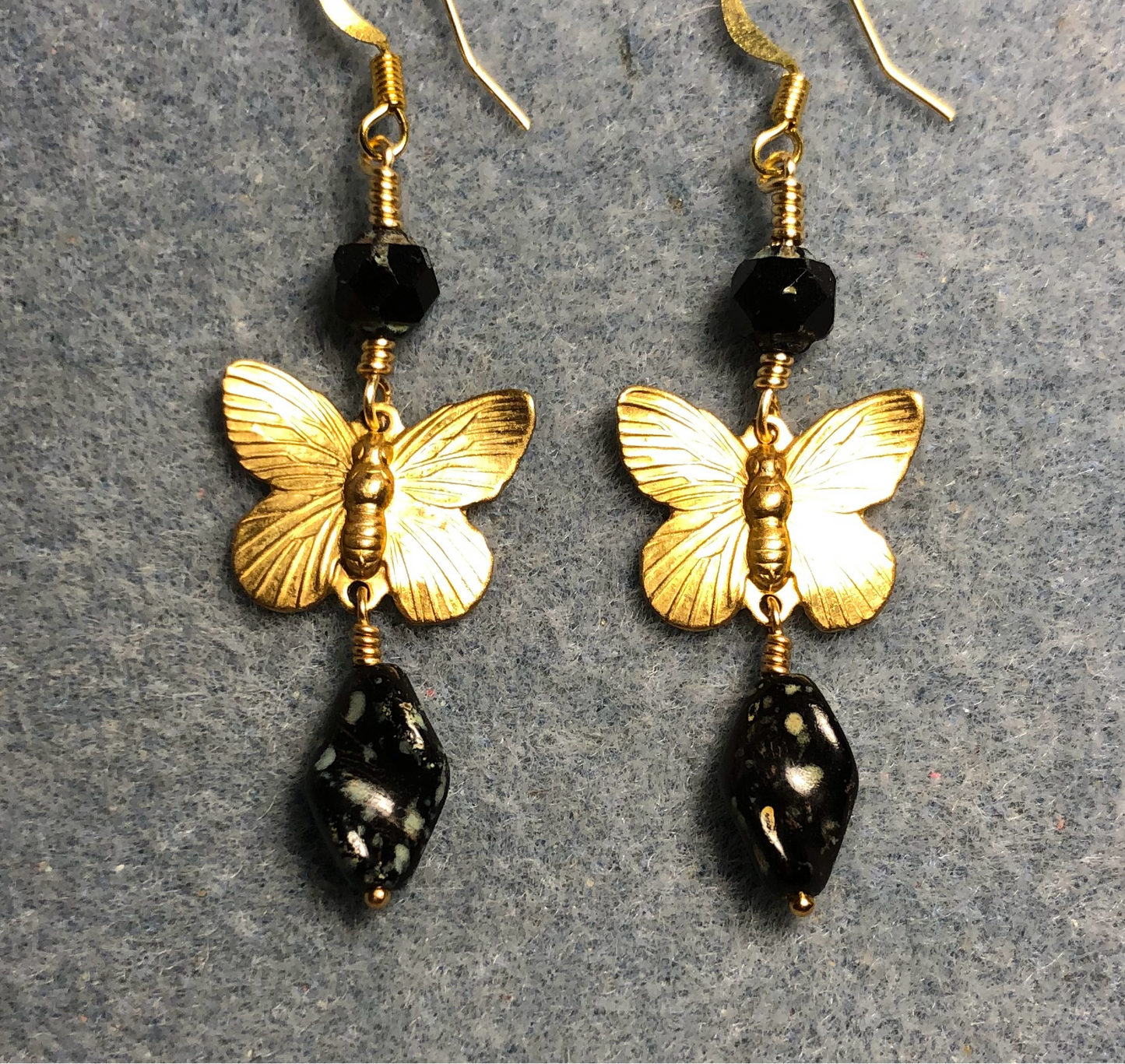 Gold butterfly charm connector earrings adorned with black Picasso Czech glass twist beads and black Picasso Czech glass beads.