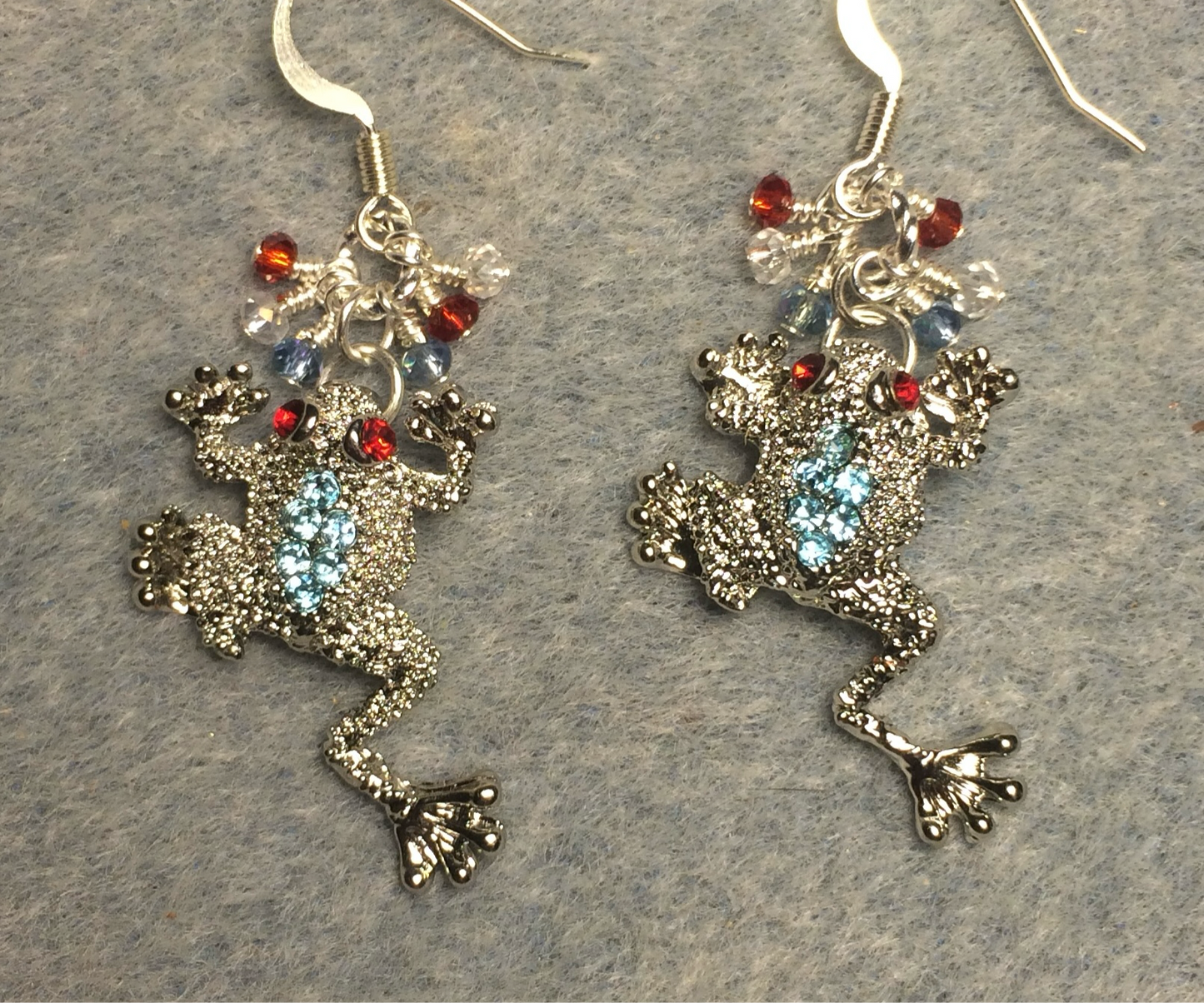 Silver, light blue, and red rhinestone frog charm earrings adorned with tiny dangling light blue, clear, and red Chinese crystal beads.