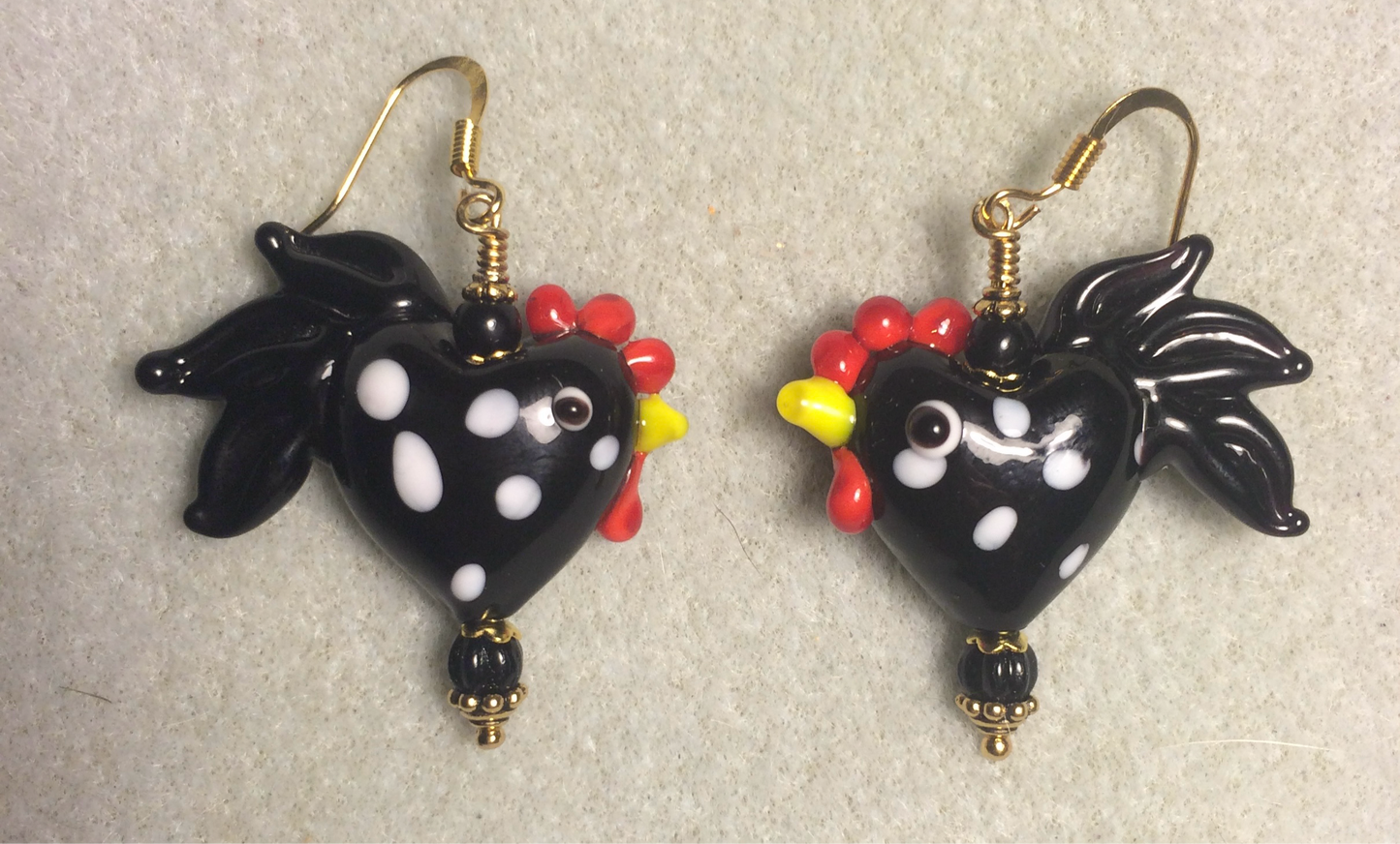 Black with white spots heart shaped lamp work rooster bead earrings adorned with black Czech glass beads.