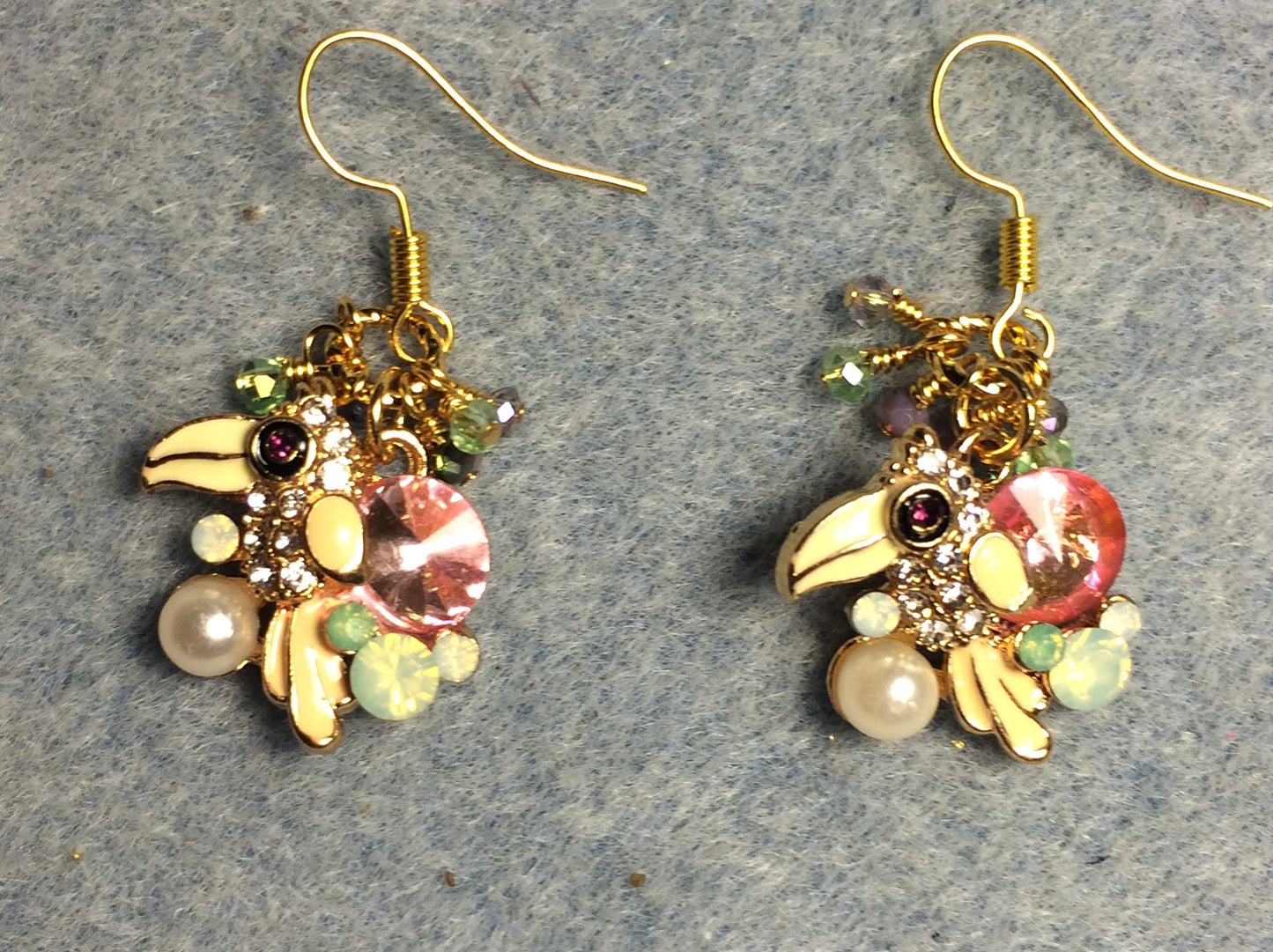 Rhinestone and pearl toucan charm earrings adorned with tiny dangling green, clear, and violet beads.