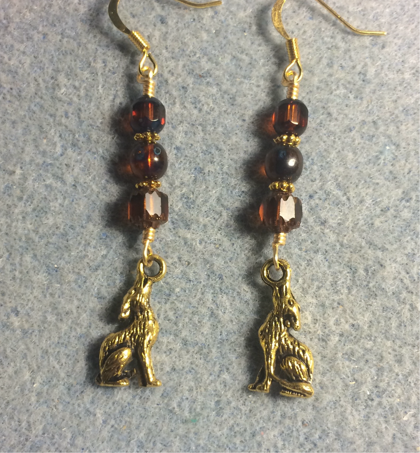 Gold howling coyote charm earrings adorned with brown Czech glass beads