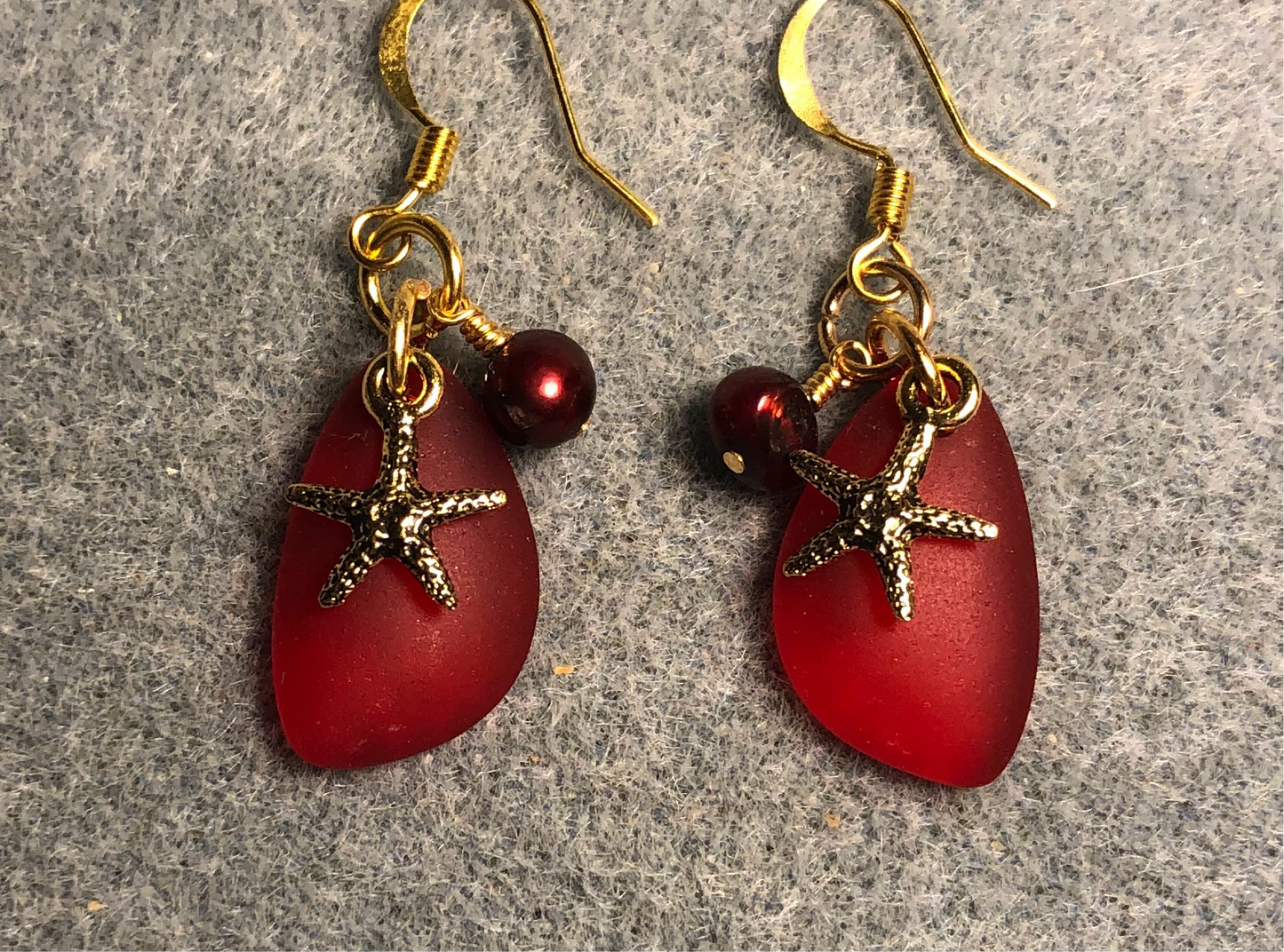Small red sea glass pendant bead earrings adorned with small gold starfish charms and small red pearl beads.
