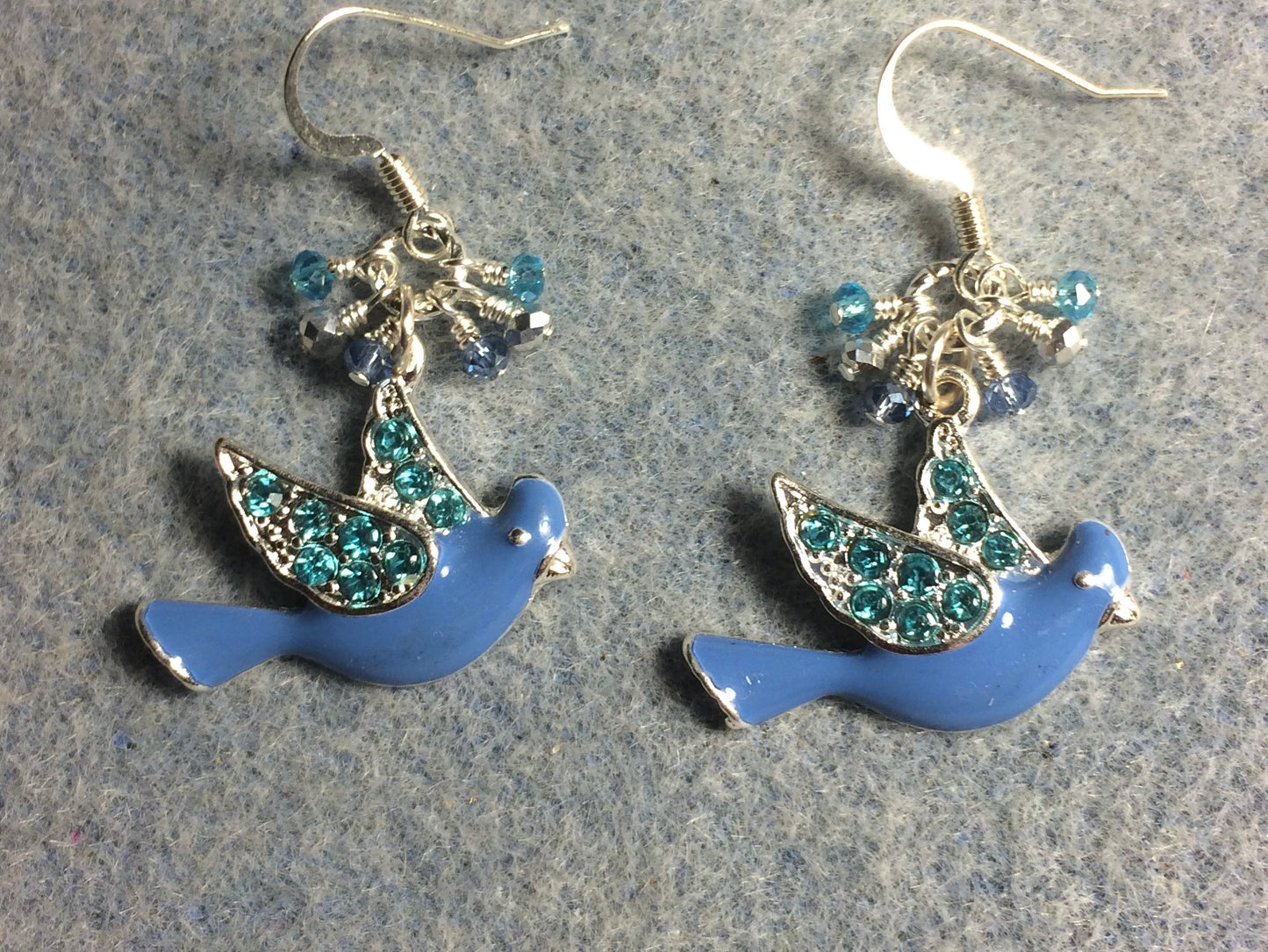 Blue and turquoise enamel and rhinestone flying dove charm earrings adorned with tiny dangling blue, silver, and turquoise Chinese crystal beads.