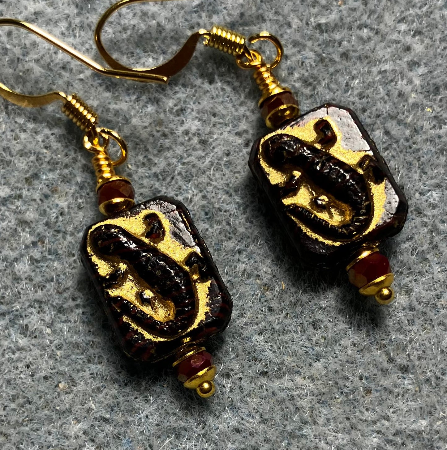 Small dark red and gold Czech glass lizard bead earrings adorned with dark red Chinese crystal beads.