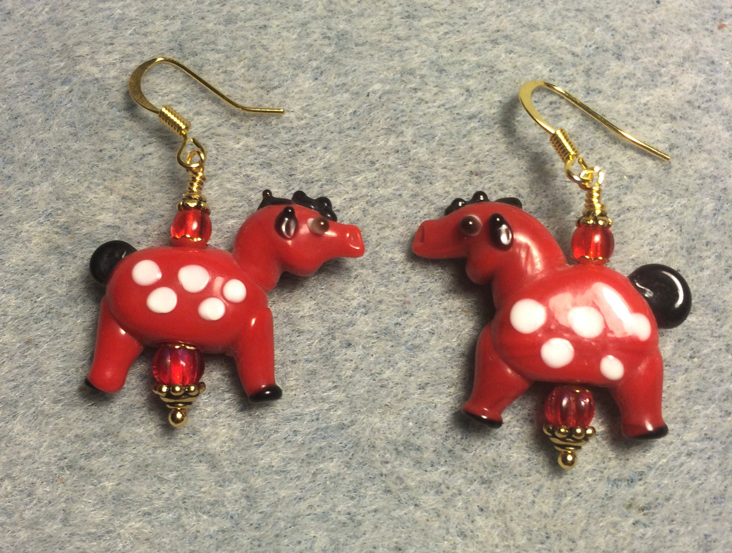 Opaque red lamp work spotted horse bead earrings adorned with red Czech glass beads.