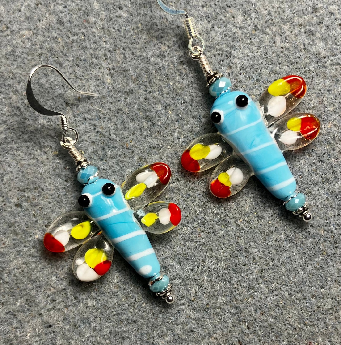 Light blue, red, and yellow lamp work dragonfly bead earrings adorned with light blue Chinese crystal beads.