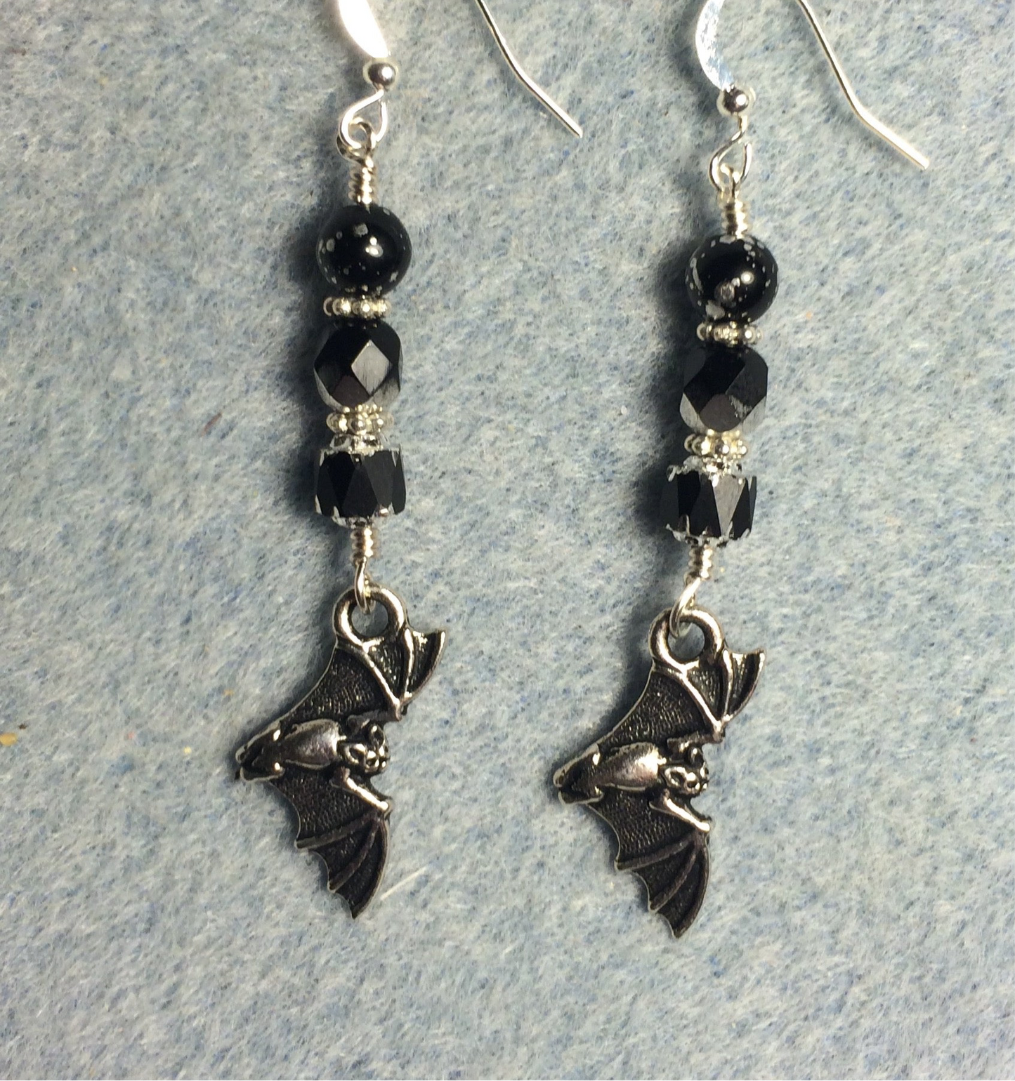 Silver flying bat charm earrings adorned with black Czech glass beads.