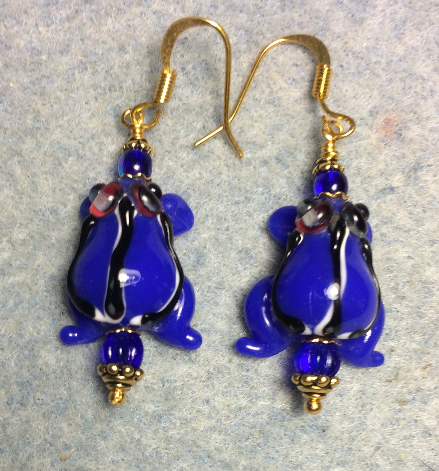Opaque bright blue lamp work striped frog bead earrings adorned with bright blue Czech glass beads.