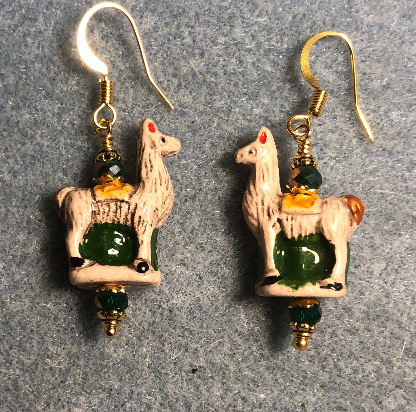 Small tan, dark green, and yellow ceramic llama bead earrings adorned with dark green Chinese crystal beads.