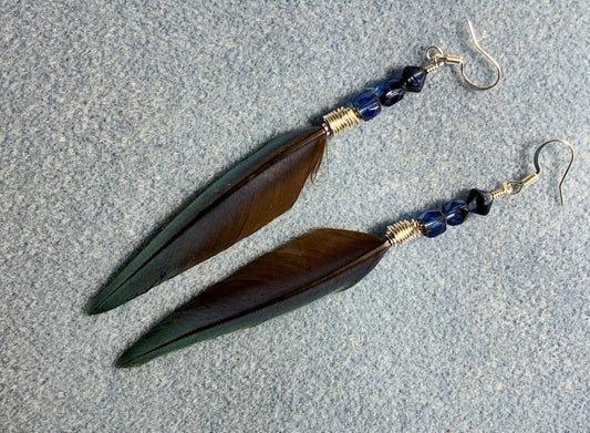 Slender scarlet macaw feather earrings adorned with dark blue Czech glass beads.