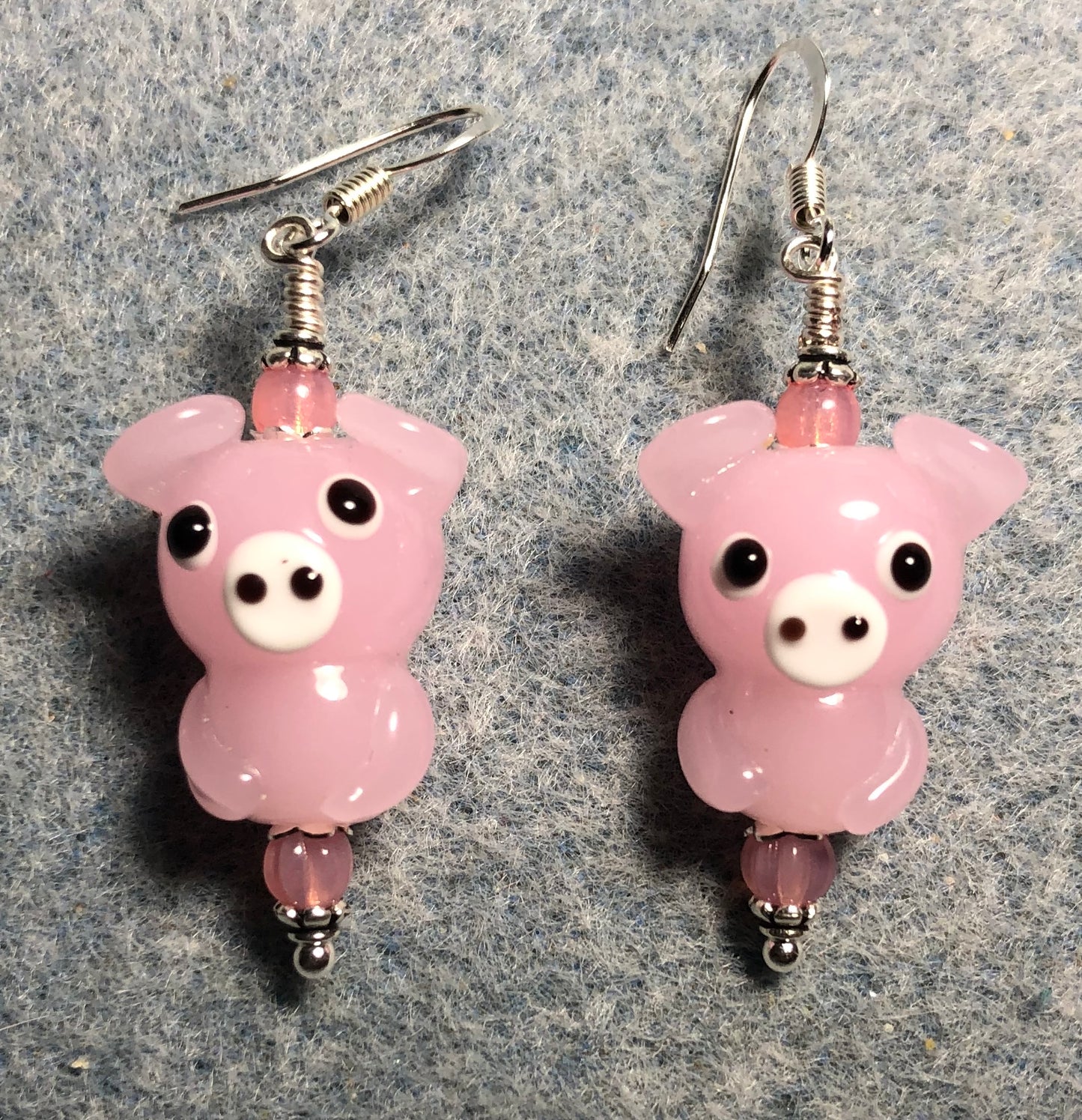Pink lamp work pig bead earrings adorned with pink Czech glass beads.