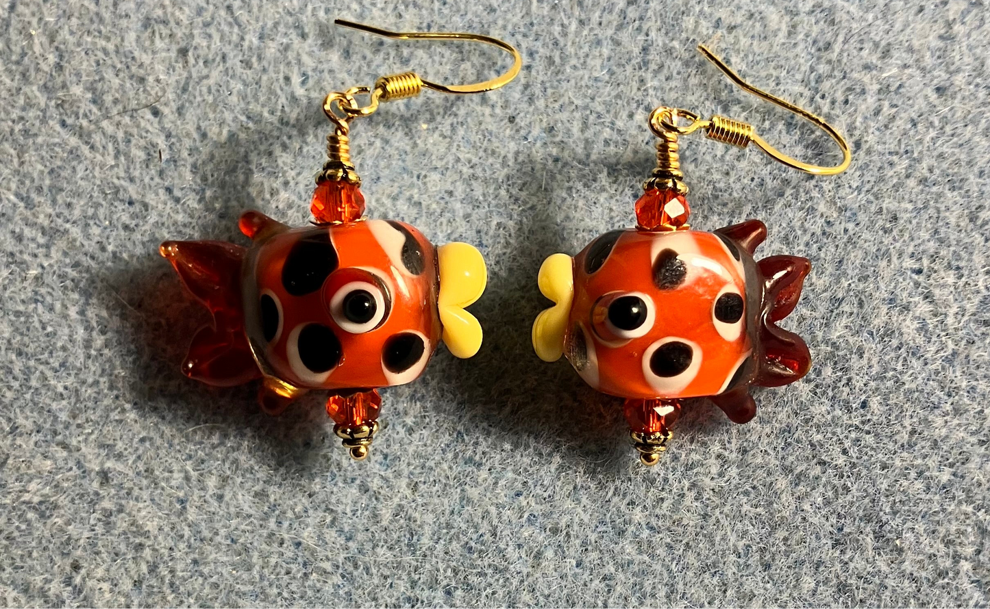 Orange and brown lamp work spotted fish bead earrings adorned with orange Chinese crystal beads.
