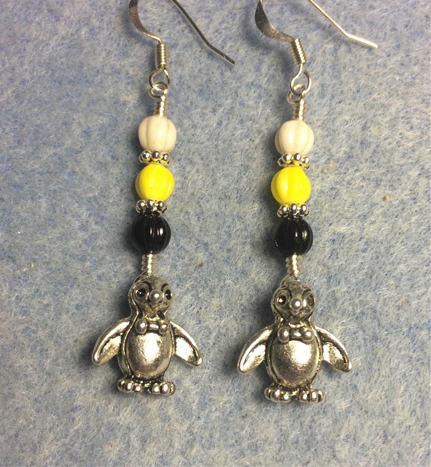 Small silver silly penguin charm earrings adorned with small black, yellow, and white Czech glass melon beads