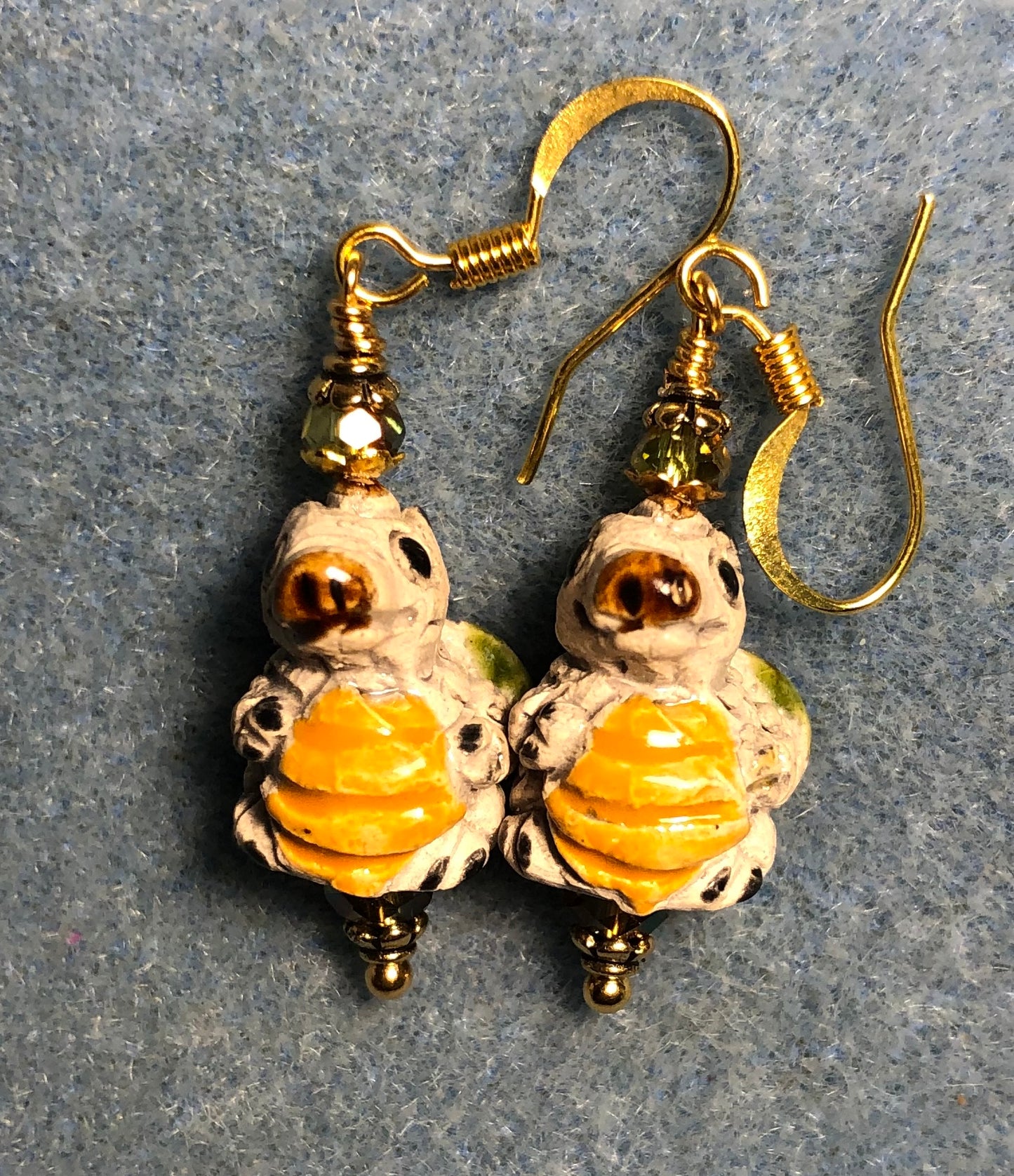 Small beige, green, and yellow ceramic alligator bead earrings adorned with sparkly olive green Chinese crystal beads.